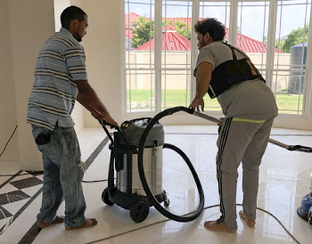 Two men using a vacuum cleaner