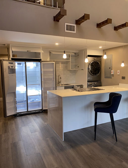Kitchen area with open fridge and table with black chair